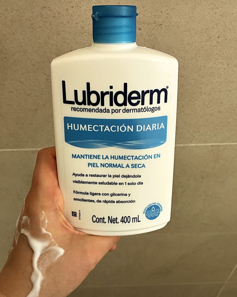 The Lubriderm bottle in my hand, with lotion on my arm